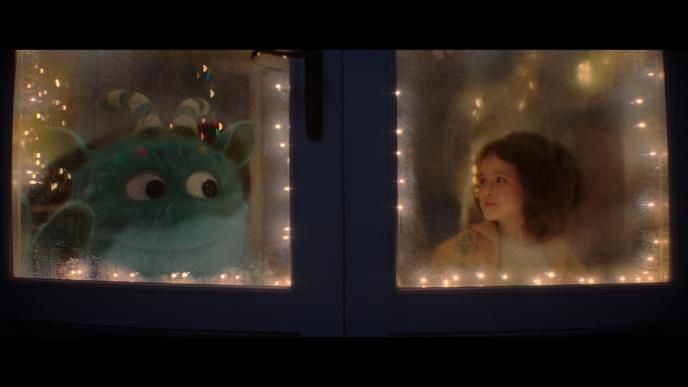 outside perspective of imaginary iggy and a child looking at each other by the window. they are in each side of the window panels. there are fairy lights. they are smiling at each other