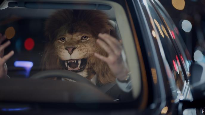 businessperson with the head of a lion in a car holding its hands up in frustration