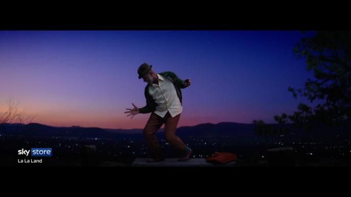 a person happily dancing on a rooftop. it is dusk