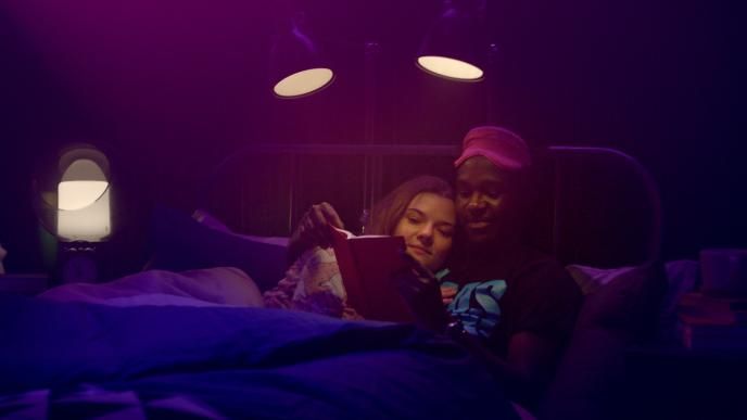 a couple cuddled up together reading a book in bed