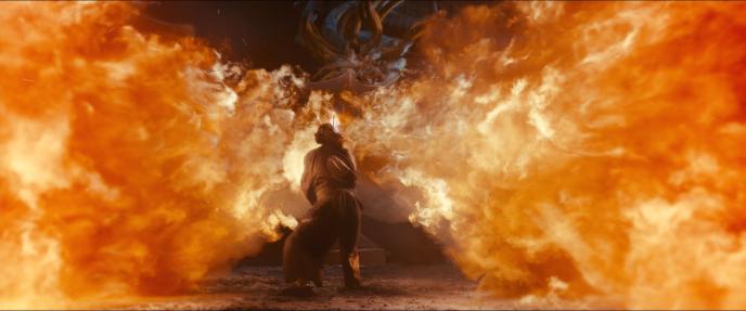 back view of actor keanu reeves as kai from 47 ronin engulfed in flames fighting a dragon
