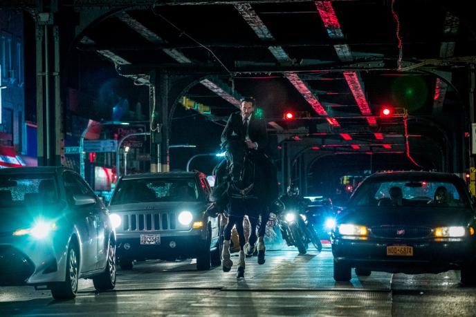 john wick riding a horse through traffic