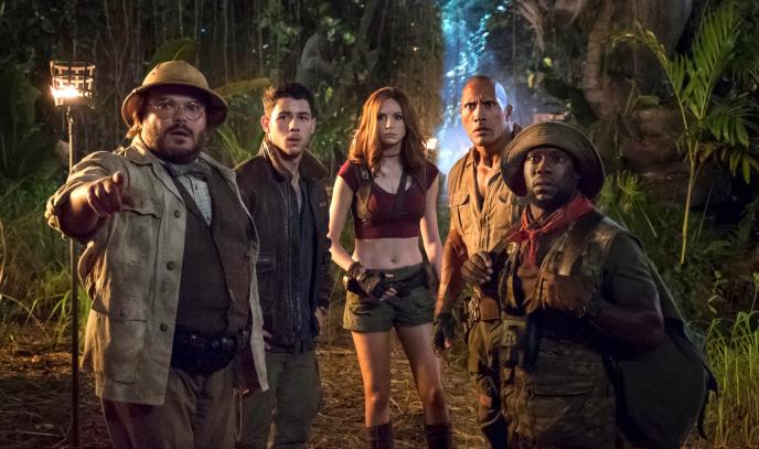 five jumanji characters standing together looking ahead to the left in a jungle