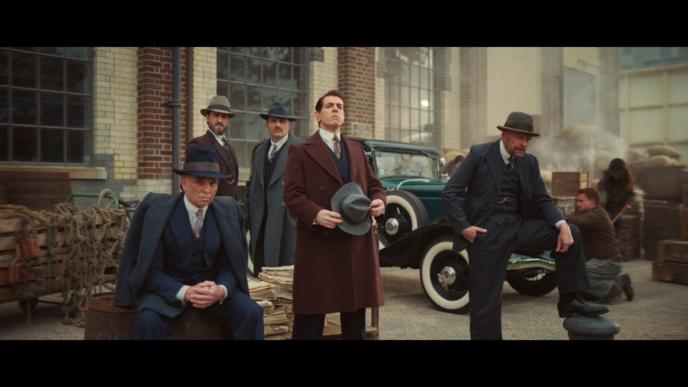 five actors on a 50s film set wearing suits and fedora hats