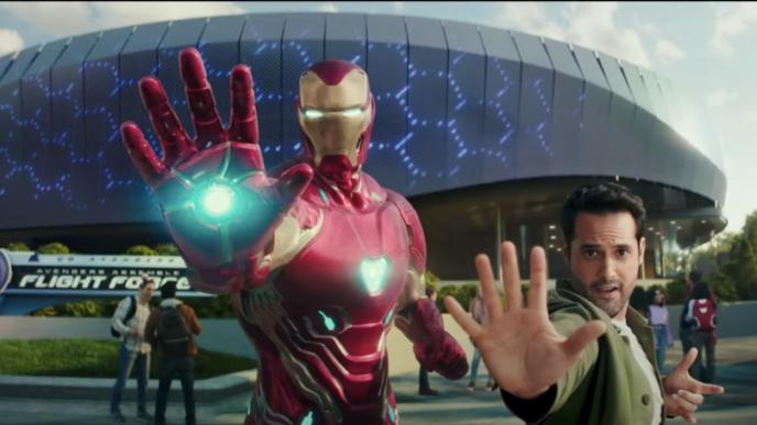a person standing next to iron man as they pose with their palms out towards the camera in front of a stadium