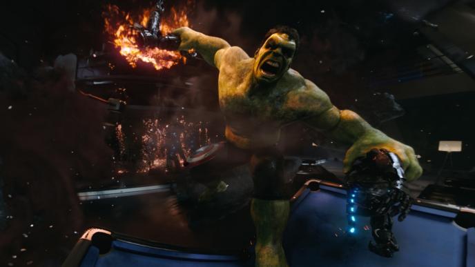 an angry hulk holding a sub-ultron in both hands. the one on the right is on fire