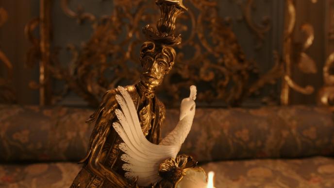 cg animated photorealistic candle holder character lumiere from beauty and the beast holding a porcelain dove as they look towards the camera