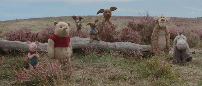 cg animated photorealistic winnie the pooh characters standing together in between a tree log in a field. from the left to the right is piglet, winnie the pooh, rabbit, roo, kanga, tigger and eeyore