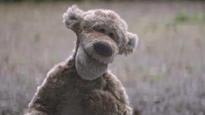 front shot of cg animated photorealistic tigger the toy looking up endearingly with his paw on his chest