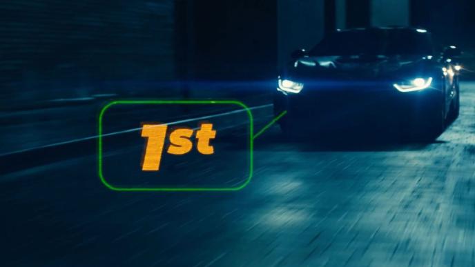 front view of a car with its headlights on. there is a holographic text that reads '1st' on its left