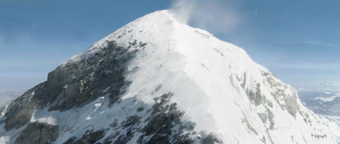 aerial view of the top of mount everest as eleven small figures in a single file are visible from the distance
