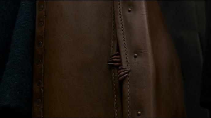 inside of a a jacket with a niffler creature's claws peaking through the slits. there are scratch marks around the jacket