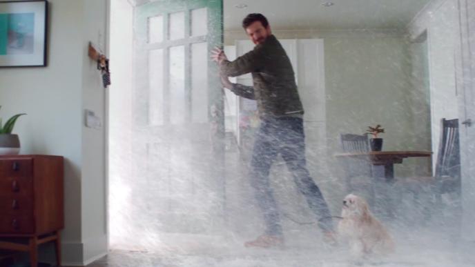 a person standing in front of a porch with their dog trying to close the door on a snow storm