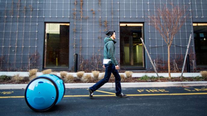 side view of a man walking with gita the autonomous mobile carrier