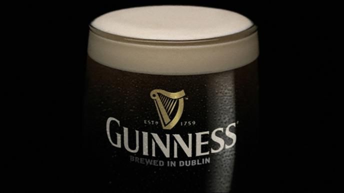 close up shot of a pint of guinness in a guinness branded pint glass