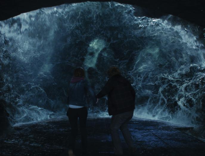 back view of hermione granger and ron weasley standing in the chamber of secrets as voldemort's horcrux face emerges through waves of water