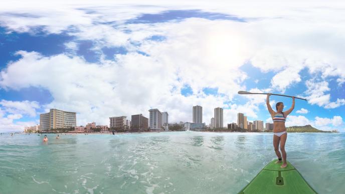 a woman holding up a paddle of a surf board overlooking the hawaiian beach and cityscape
