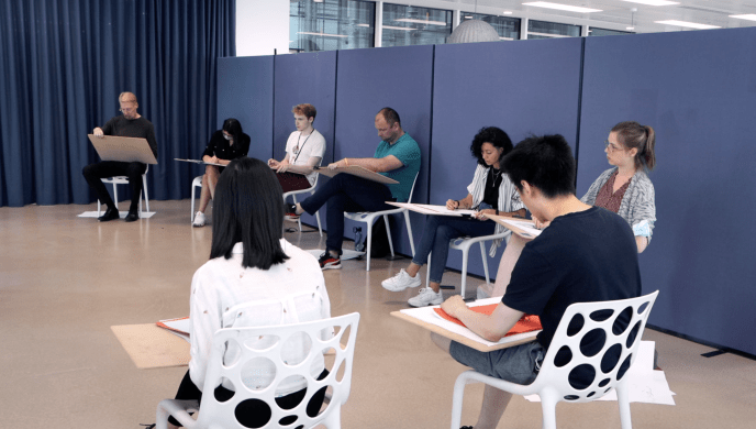 a group of people sitting at desk sketching on drawing pads