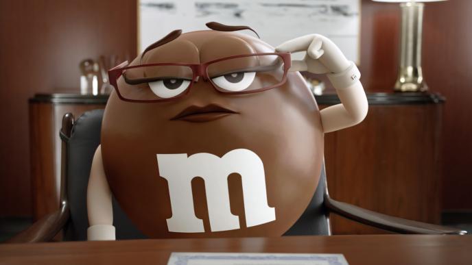 cg animated ms. brown chocolate m&m holding her glasses with a stern expression
