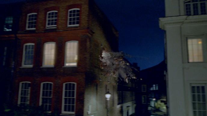 nighttime setting of a street view of a georgian house that has a an explosion on the side of the wall