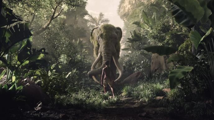 back view of mowgli looking up at an elephant in a jungle