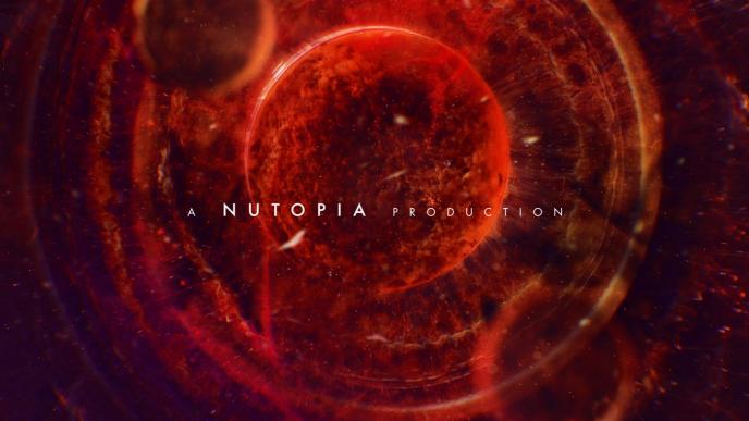 a red gaseous planet encircled with rings with the text 'a nutopia production' in the centre