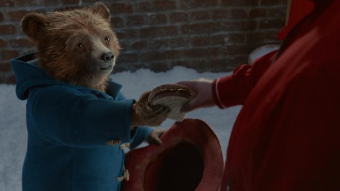 cg animated paddington bear giving a sandwich to a person
