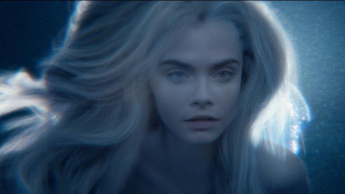 face close up of cara delevigne floating in water with a luminous light in the back