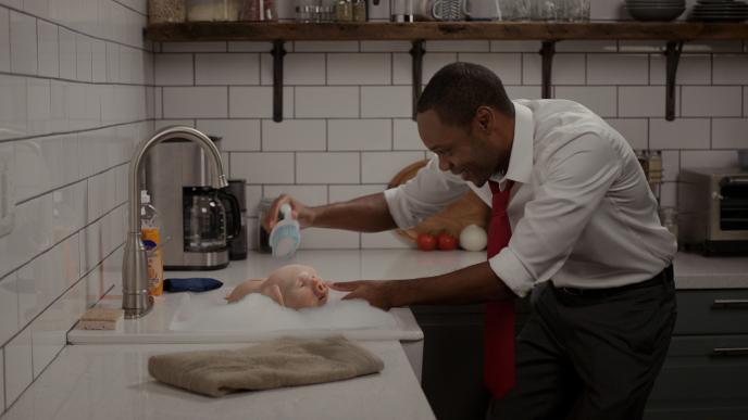 a person giving a cg animated photorealistic piggy bank a bath in a kitchen sink