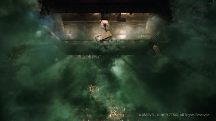aerial view of spider-man standing at the top of a construction building that is surrounded in green mist