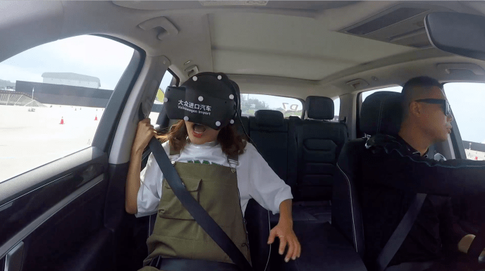 two people in a car. one of them is driving and the passenger is wearing a vr headset