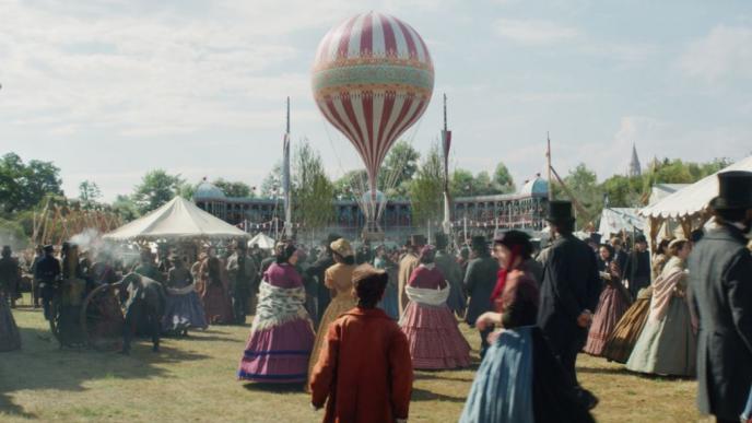 19th century fun fair bustling with people with a hot air balloon in the centre
