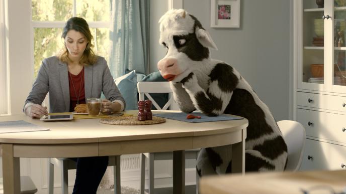 a woman sitting at a breakfast table with a cg animated cow character