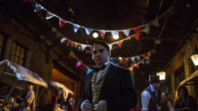 a victorian man standing in front of a film set in a victorian era street