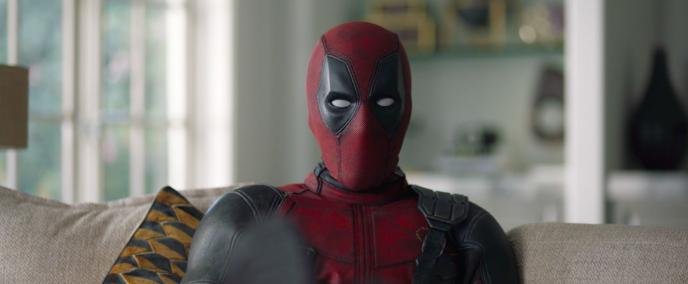 deadpool character sitting on a sofa looking directly into the camera