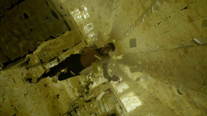 a train carraige covered in yellow post-it notes as a person runs through the centre