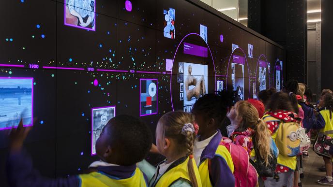 children on a school trip interacting with a screen that has modern art infographics