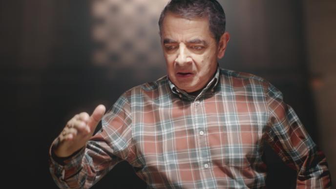 actor rowan atkinson waving a hand