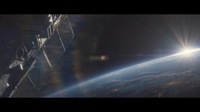 the sun peaking through the curvature of the planet as a satellite floats by