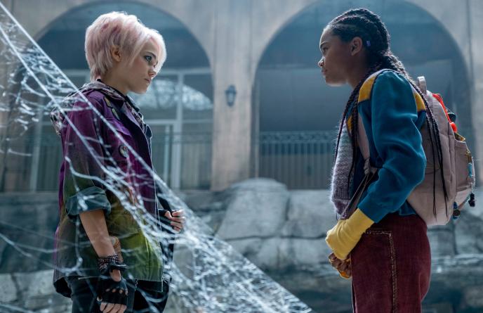 side view of oona laurence as liz lerue on the left and tamara smart as kelly ferguson on the right looking at each other in an abandoned building covered in spider webs
