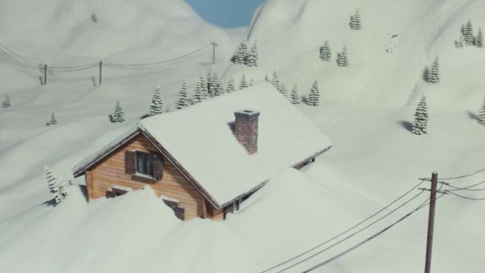 aerial view of a house amongst snowy mountains submerged in snow