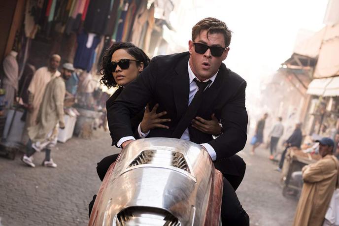 chris hemsworth as agent h driving a motorcycle as tessa thompson as molly sits in the back