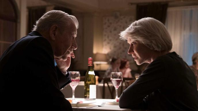 side view of betty mcleish and roy courtnay looking at each other while sitting at a dinner table in a dimly lit restaurant