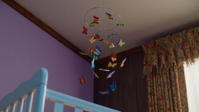 a butterfly crib mobile above a blue cot in a purple room