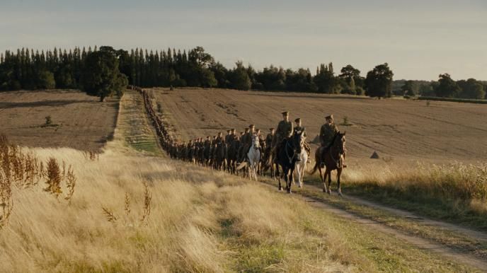 an army on horses moving through a field
