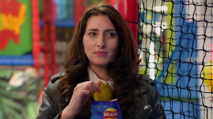 close up of a woman in a kidzone playground looking to the right while holding a crisp