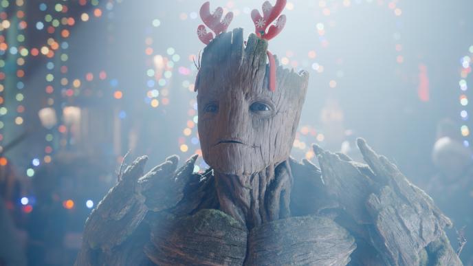 Groot, lit by a spotlight, wearing Christmas antlers