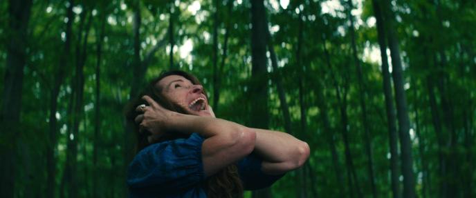 Julia Roberts in Netflix's film "Leave the World Behind". She stands in a green woodland with her hands over her ears, screaming