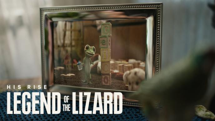 A picture frame contains a photo of the GEICO gecko as a baby. The words "His Rise. Legend of the Lizard" are on the photo 