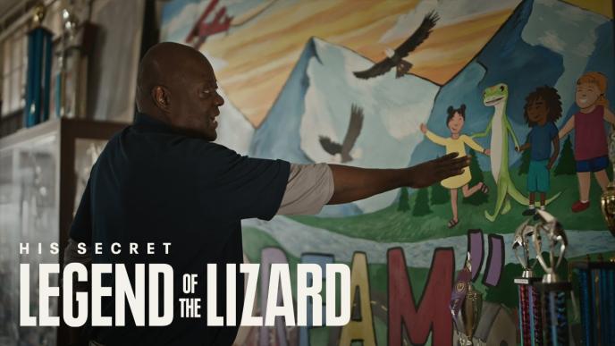 A man points to a painted mural of the GEICO gecko holding a girl's hand. The words "His Secret. Legend of the Lizard" are on the photo